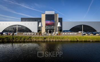 Vooraanzicht van kantoorpand aan de van Cleeffkade 15 in Aalsmeer, met zicht op parkeerplaats en ingangen.