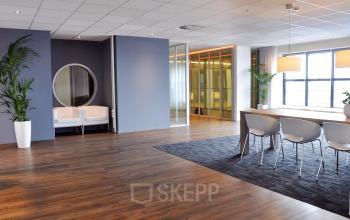 Interieur van kantoorpand op Van Cleeffkade 15 in Aalsmeer met houten vloer, vergadertafel, stoelen en planten.