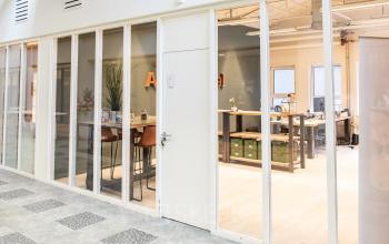 Kantoorruimte huren in een modern kantoorpand op van Cleeffkade 15, Aalsmeer. Gezellige werkplekken met glazen wanden en functionele inrichtingen. Personen zijn bezig met werkzaamheden.