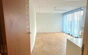 Lichte kantoorruimte in Abcoude met houten vloer en grote ramen, beschikbaar voor huur.