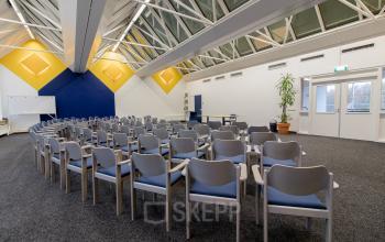 Foto van een kantoorpand aan Bedrijvenpark Twente 305 in Almelo, met een ruime, modern ingerichte vergaderruimte voorzien van stoelen, whiteboard en een projector.