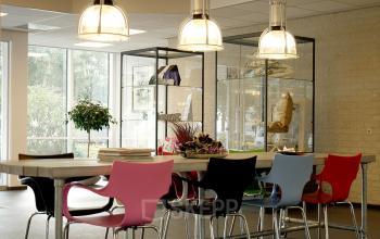 Binnenaanzicht van een kantoor in Bedrijvenpark Twente 305, Almelo. Gemeubileerde werkruimte met kleurrijke stoelen en decoratieve lampen.