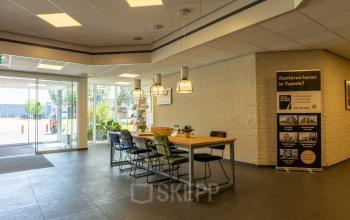 Inloop van een kantoorpand op Bedrijvenpark Twente 305 in Almelo met tafel en stoelen, geschikt voor huur van kantoorruimte.