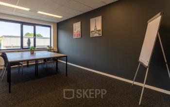 Ruime kantoorruimte te huur in Almelo met grote tafel en stoelen, voorzien van natuurlijk licht en inspirerende wanddecoratie.