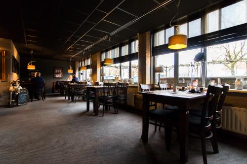 Interieur van een kantoorpand op Bedrijvenpark Twente 305, Almelo, met enkele mensen zittend aan tafels. Sfeerverlichting en grote ramen zorgen voor een aangename werkomgeving.