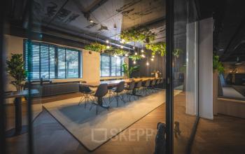 Moderne kantoorpand met grote vergadertafel en stijlvolle verlichting aan de Brugstraat 9-13 in Almelo. Ideaal om kantoorruimte te huren met natuurlijke lichtinval en een frisse inrichting.