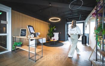 Kantoorruimte huren aan de Brugstraat 9-13 in Almelo met moderne, lichte inrichting en uitnodigende wachtruimte. Een persoon loopt door de ruimte, klaar voor een zakelijke ontmoeting.