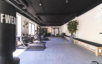 Moderne sportruimte in een kantoorpand op Brugstraat 9-13, Almelo, met fitnessapparatuur en lichte muren. Perfect voor bedrijven die kantoorruimte willen huren met extra faciliteiten voor welzijn en activiteit.