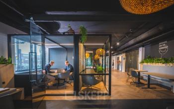 Moderne kantoorruimte huren met glazen vergaderruimte in Almelo, Brugstraat 9-13. Verschillende werkplekken en sfeerlicht, ideaal voor zakelijke meetings.