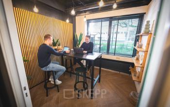 Moderne kantoorruimte met hoge tafels in Almelo, Brugstraat 9-13, waar twee personen samenwerken aan laptops.