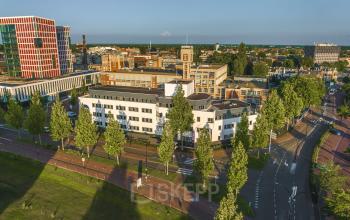 Luchtfoto van het kantoorpand aan de Egbert Gorterstraat 2-14 in Almelo, omringd door bomen en straten. Ideale locatie voor kantoorruimte huren in een stedelijke omgeving met goede toegankelijkheid.