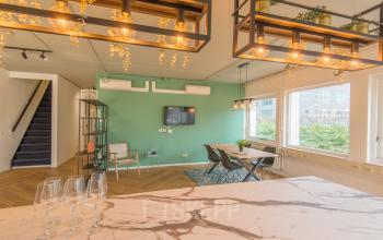Stijlvol ingerichte kantoorruimte huren in Almere Poort, met moderne meubels en groen interieur. Grote ramen bieden veel daglicht. Perfect voor creatieve werkplekken of vergaderingen.