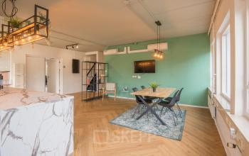 Kantoorruimte op Kabelstraat 5 in Almere Poort met moderne inrichting, houten vloer, groen geverfde muur, vergadertafel en stoelen. Geschikt voor kantoorruimte huren.