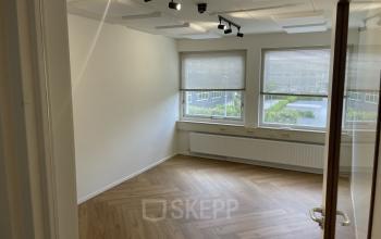 Lichte kantoorruimte met houten vloer op Kabelstraat 5, Almere Poort. Grote ramen met jaloezieën bieden uitzicht en natuurlijk licht, ideaal voor kantoorruimte huren.