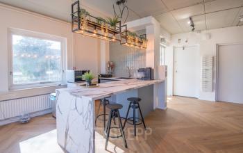Moderne kantoorruimte met stijlvolle pantry aan Kabelstraat 5, Almere Poort. Houten vloer, marmeren aanrecht en hangende lampen creëren een warme sfeer voor wie een kantoor huren wil.