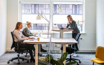 Kantoorruimte aan de P.J. Oudweg 41 in Almere Stad met drie mensen druk bezig aan bureaus, laptops open voor werk. Zonlicht komt naar binnen door grote ramen.