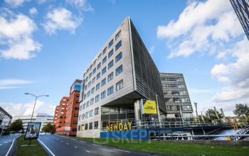 Het moderne kantoorpand gelegen aan P.J. Oudweg 41 in Almere Stad, Almere, met een opvallend hoekig ontwerp en ruime parkeergelegenheid.