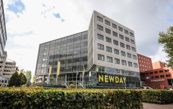 Exterieur van kantoorpand op P.J. Oudweg 41, Almere Stad, met moderne glazen gevel, geel NEWDAY logo en aangrenzende kantoren.