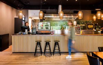 Kantoorpand Markerkant 1310 in Almere Stad met een ingerichte pantry met barstoelen en een personeelslid achter de toonbank.