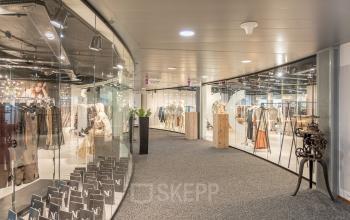 Glazen wand in een kantoorpand aan Veluwezoom 5, Almere Veluwsekant, met een moderne uitstraling. Licht interieur zichtbaar door de etalage met diverse displays in een presentatieomgeving.