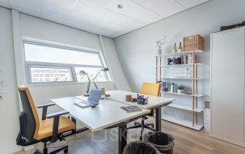 Kantoorruimte huren op Veluwezoom 5 in Almere Veluwsekant, ingericht met houten vloer, twee bureaus met stoelen, en planken tegen de muur, geschikt voor productief werk.