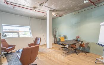 Kantoorruimte huren in Almere Veluwsekant met lichte houten vloer, comfortabele stoelen, vergadertafel en raam dat veel natuurlijk licht binnenlaat.