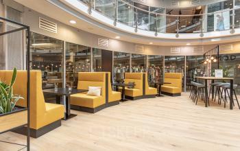 Gezellige moderne werkruimte met gele zitbanken en hoge tafels in Veluwezoom 5, Almere. Ideaal voor kantoorruimte huren.