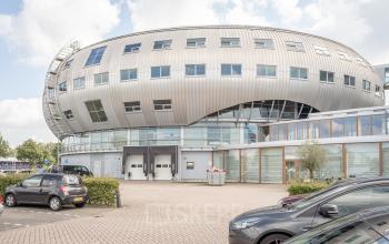 Modern kantoorpand gelegen op Veluwezoom 5 in Almere, met een karakteristieke gebogen architectuur en parkeergelegenheid voor de deur.