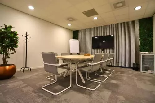 Moderne vergaderruimte in kantoorpand Leidse Schouw 2, Alphen aan den Rijn, met groot scherm, tafel en stoelen. Ideale plek om kantoorruimte te huren voor meetings. Groenaccenten en flip-over aanwezig.