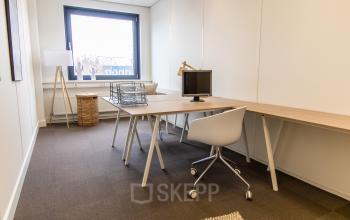 Moderne kantoorruimte huren aan de Europalaan 16, Alphen aan den Rijn, met houten bureau, comfortabele stoel, monitor en grote raam voor veel natuurlijk licht.