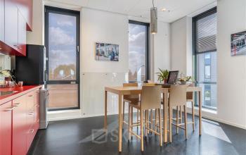 Kantoorpand Flemingweg 8 in Alphen aan den Rijn; gemeubileerde ruimte met hoge tafel en barkrukken, rode keukenkasten, grote ramen met veel natuurlijk licht.