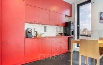 Rode pantry in kantoorpand op Flemingweg 8, Alphen aan den Rijn, met moderne keukenapparatuur en houten eettafelset, ideaal voor een korte pauze of lunch.