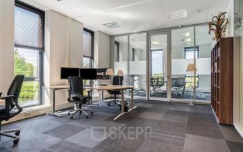 Kantoorpand Flemingweg 8 in Alphen aan den Rijn met grote ramen, bureaus, stoelen, en vergaderruimte achter glazen wanden.