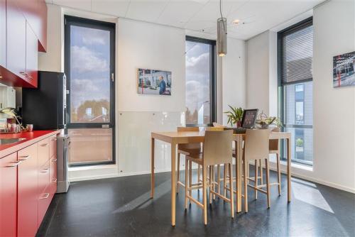 Kantoorpand Flemingweg 8 in Alphen aan den Rijn; gemeubileerde ruimte met hoge tafel en barkrukken, rode keukenkasten, grote ramen met veel natuurlijk licht.