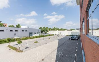 Buitenzijde van kantoorpand aan Spoetnik 10-64 in Amersfoort Calveen met parkeerplaats en omliggende gebouwen.