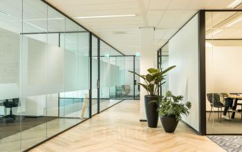 Moderne kantoorruimte te huur in Amersfoort Calveen met glazen wanden, houten vloer en groene planten. Ruim en licht met toegang tot vergaderruimte. Ideaal voor creatieve zakelijke bijeenkomsten en productief werken.