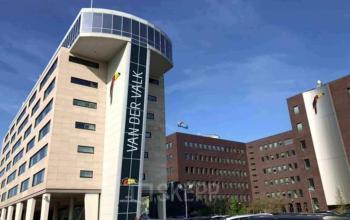 Kantoorpand aan Ruimtevaart 24 in Amersfoort Calveen, omringd door parkeerplaatsen en onder een heldere blauwe lucht.