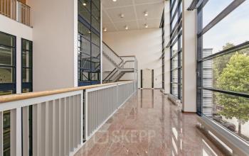 Binnenzicht van modern kantoorpand op Astronaut 28, Amersfoort Calveen met glazen gevel en ruime gang. Een lichte omgeving die perfect is voor kantoorruimte huren. Geen personen aanwezig op de foto.