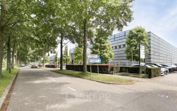 Exterieur van kantoorpand gelegen op Astronaut 28 in Amersfoort Calveen, omgeven door groene bomen en naast een weg met parkeergelegenheid. Ideale locatie voor wie op zoek is naar een kantoorruimte huren.