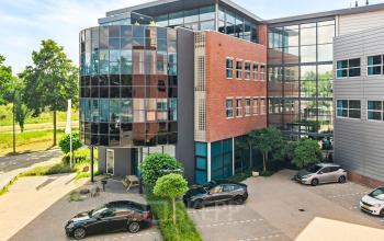 Modern kantoorpand met glazen en bakstenen gevel op Maanlander 43, Amersfoort Calveen, met meerdere geparkeerde auto's ervoor. Ideale optie voor kantoorruimte huren.