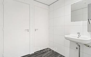 Wit betegelde toiletruimte in kantoorpand met wastafel en spiegel op Maanlander 43, Amersfoort Calveen. Kantoorruimte huren in een nette omgeving.