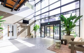 Heldere en moderne ontvangstruimte met grote ramen, planten en stijlvolle meubels. Ideaal voor kantoorruimte huren in Amersfoort Calveen.