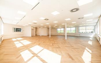 Ruime en lichte kantoorruimte te huur op Maanlander 43, Amersfoort Calveen. Grote ramen zorgen voor natuurlijk licht over de houten vloer, ideaal om kantoren volledig naar wens in te richten.