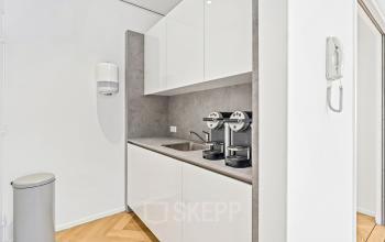 Moderne kantoorpantry met witte kasten en espressomachines, gelegen op Maanlander 43 in Amersfoort Calveen. Ideale plek voor een snelle koffiepauze tijdens het kantoorruimte huren.