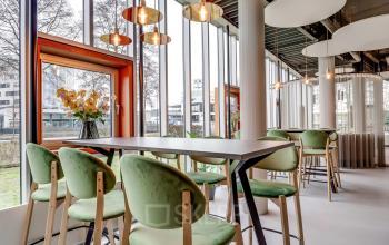 Moderne kantoorruimte met grote ramen en groene stoelen, ideaal voor wie kantoorruimte wil huren in Amersfoort Calveen.