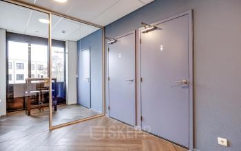 In het kantoorpand op Maanlander 47 in Amersfoort Calveen zijn twee deuren naar het toilet te zien, met spiegels en een hoge tafel in de achtergrond.