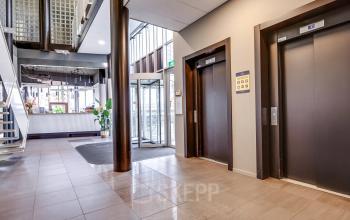 Ingang van een kantoorpand op Maanlander 47, Amersfoort Calveen, met liften en een ontvangstruimte met balie. Ideaal voor kantoorruimte huren.