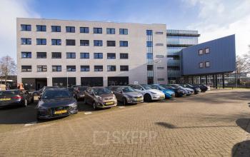 Exterieur van het kantoorpand aan Maanlander 47 in Amersfoort Calveen, met meerdere geparkeerde auto's ervoor.