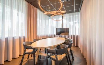 Vergaderruimte in kantoorpand op Maanlander 47, Amersfoort Calveen, met ovale tafel, zes stoelen en een televisie. Ideaal voor wie een kantoorruimte wil huren.