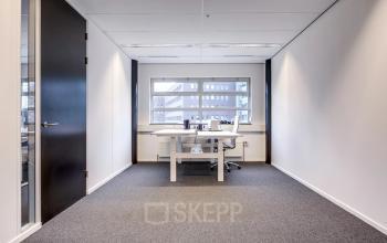 Lichte kantoorruimte met grijze vloerbedekking op Maanlander 47 in Amersfoort Calveen. Perfect voor wie kantoor wil huren met een rustige werksfeer. Witte muren en een groot raam zorgen voor veel natuurlijk licht.